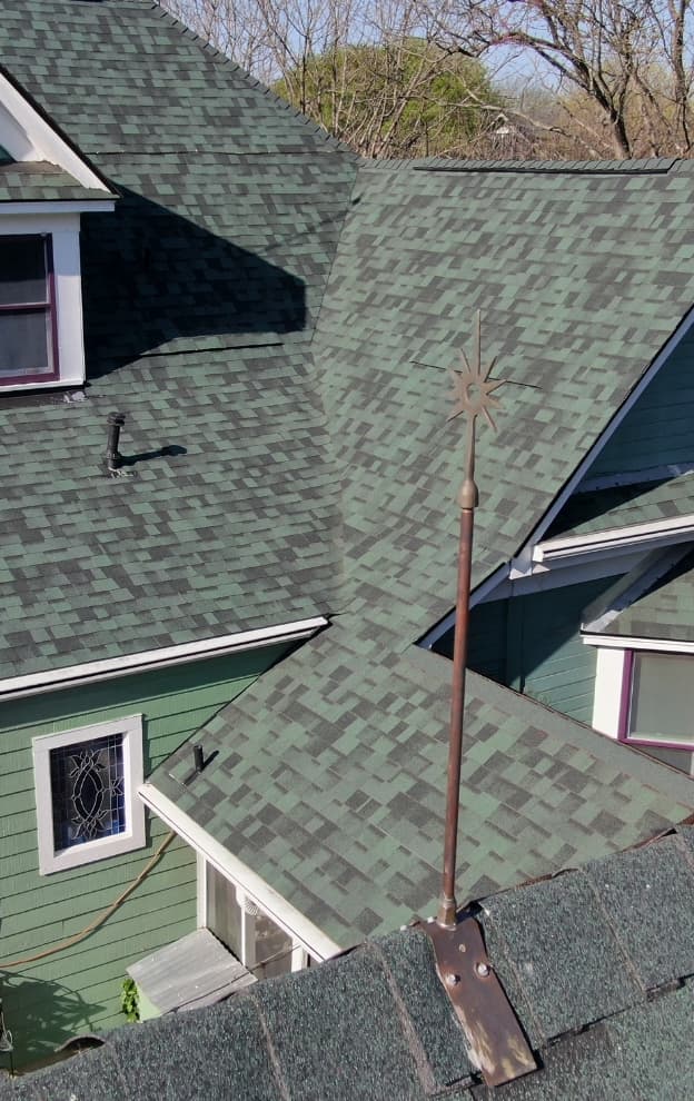 Detailed view of green architectural shingles with copper lightning rod accent