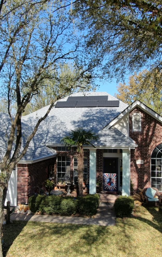 Brick home with new gray shingle roof and solar panels in a Texas neighborhood